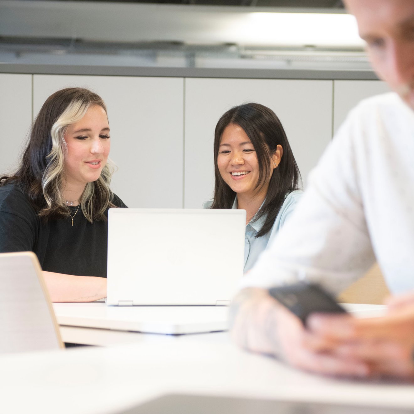 Zwei Frauen schauen auf einen Laptop und lachen