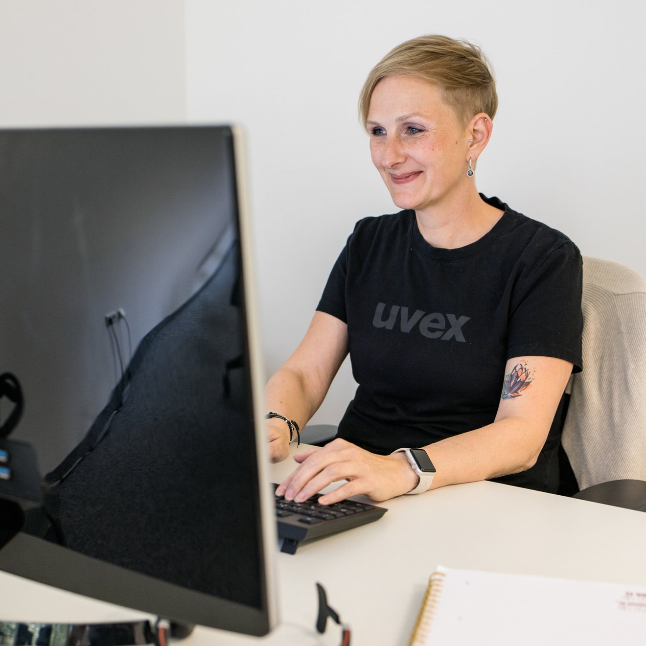 Eine Frau in uvex T-Shirt arbeitet an ihrem Laptop