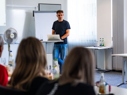 Lukas präsentiert vor einem Publikum Inhalte der Ausbildung