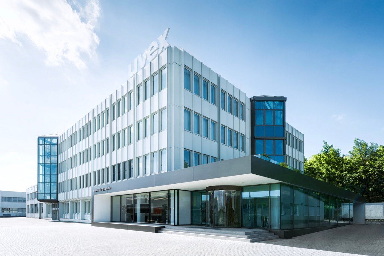 Modernes Bürogebäude der uvex group mit verglastem Eingangsbereich und Unternehmenslogo an der Fassade.