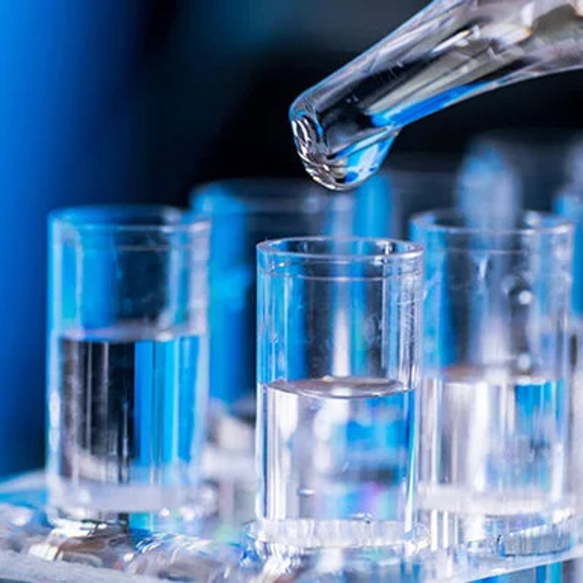 Eine Flüssigkeit wird aus einem Glasbehälter in ein kleines Glas gefüllt