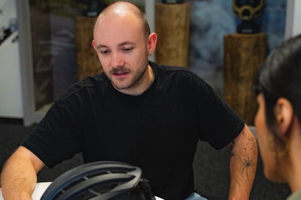Ein uvex Werkstudent zeigt etwas an einem Fahrradhelm
