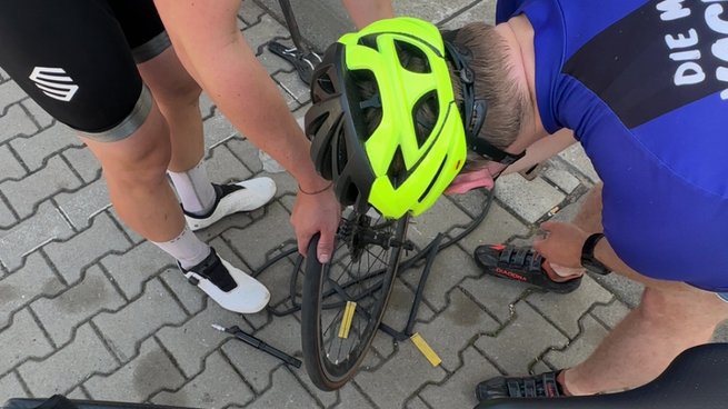Zwei Personen reparieren ein Rad vom Fahrrad