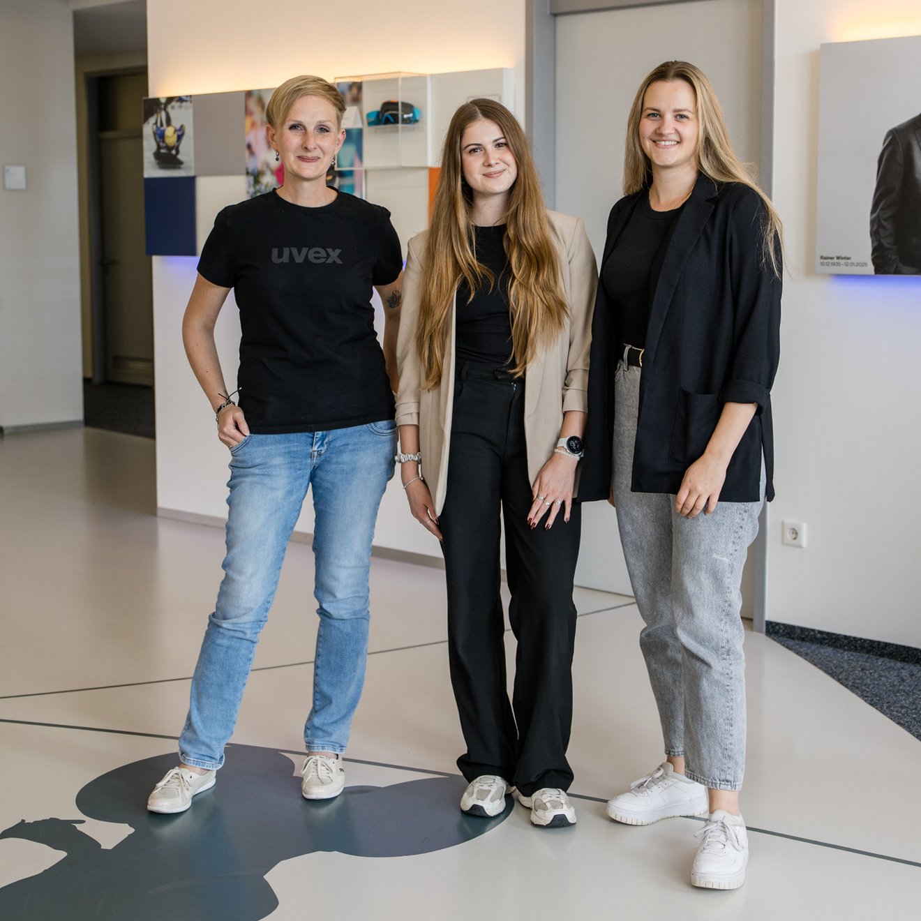 Drei Frauen stehen nebeneinander in einem Flur und lachen