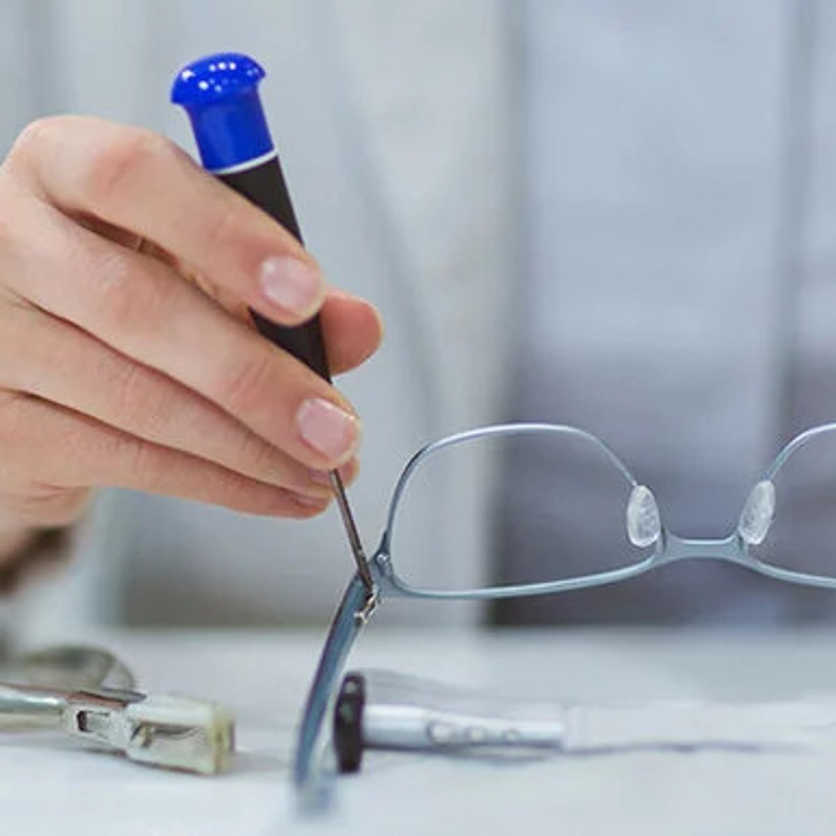 Eine Person schraubt mit einem Schraubenschlüssel an einer Brille