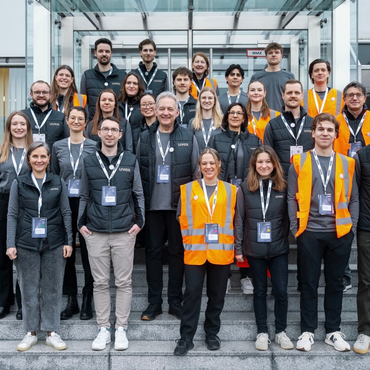 Eine große Gruppe an Personen steht auf einer Treppe und lächelt in die Kamera.