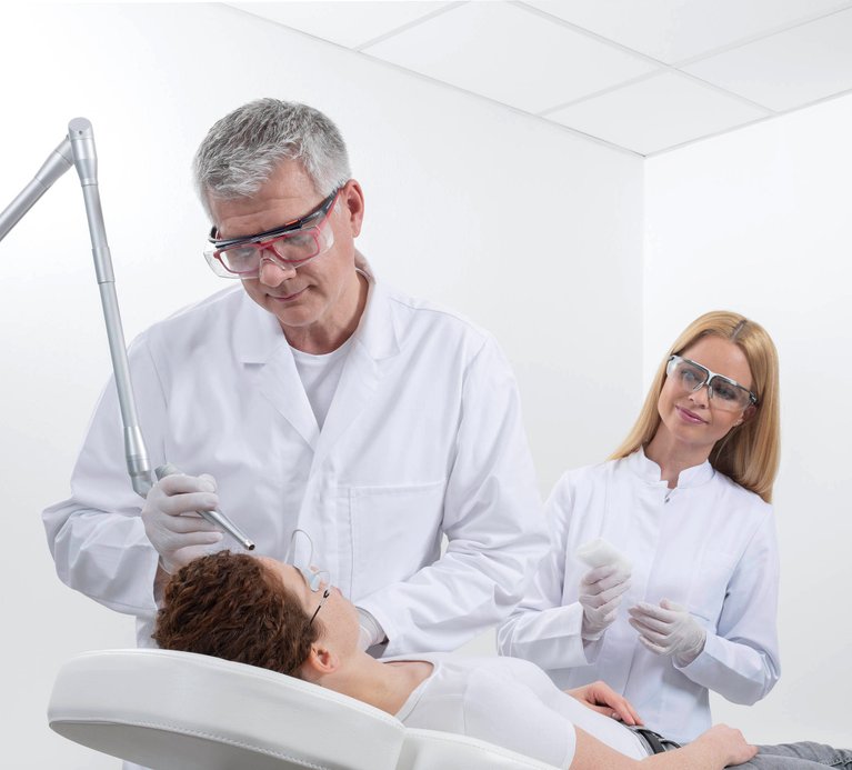 Ein Arzt führt eine Laserbehandlung durch und trägt eine Laserschutzbrille