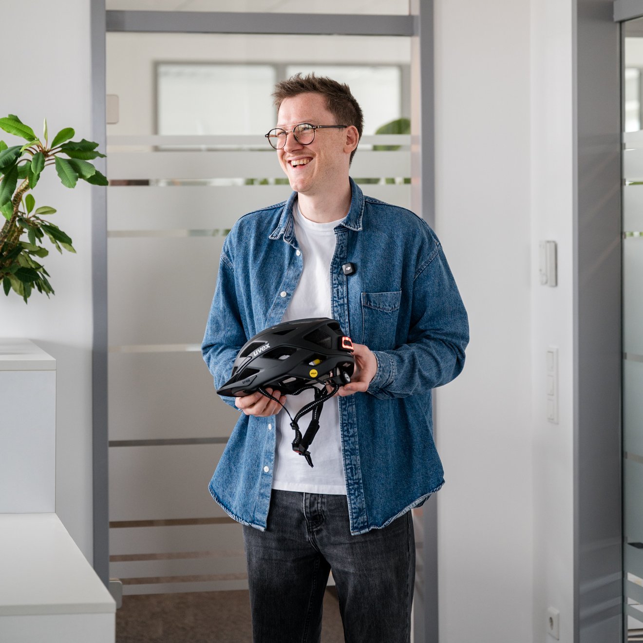 Ein junger Mann mit schwarzem Radhelm in der Hand
