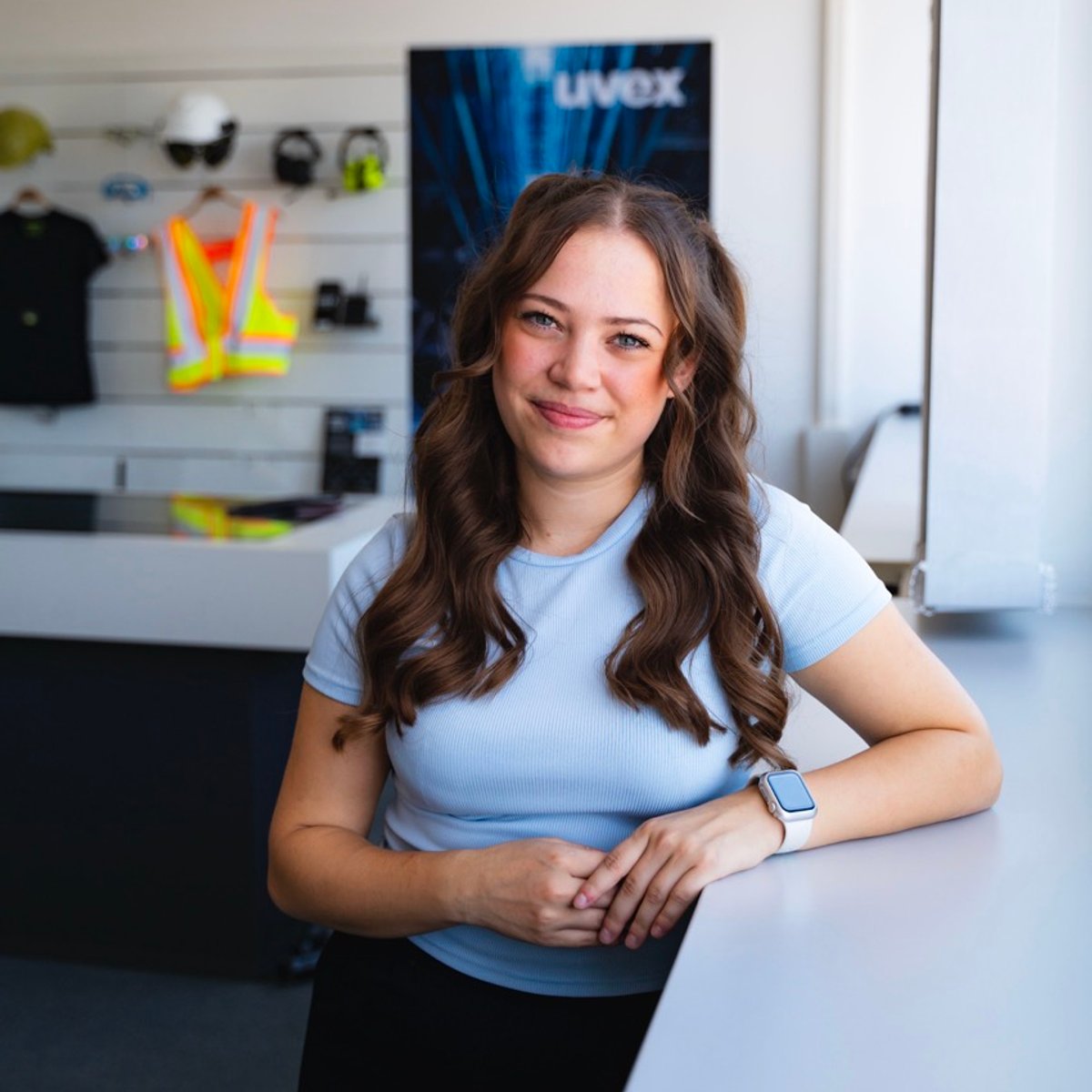 Eine uvex Werkstudentin steht vor einer Wand voller uvex Produkte