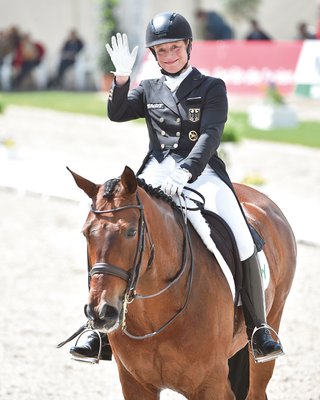 Isabel Werth sitzt auf einem Pferd und winkt