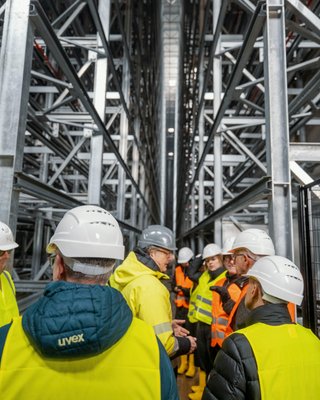 Personen in Sicherheitskleidung stehen im Hochregallager