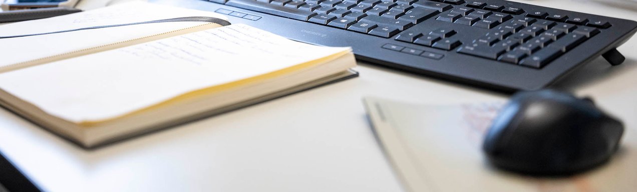 Nahaufnahme einer Tastatur, Maus und eines Notizblockes