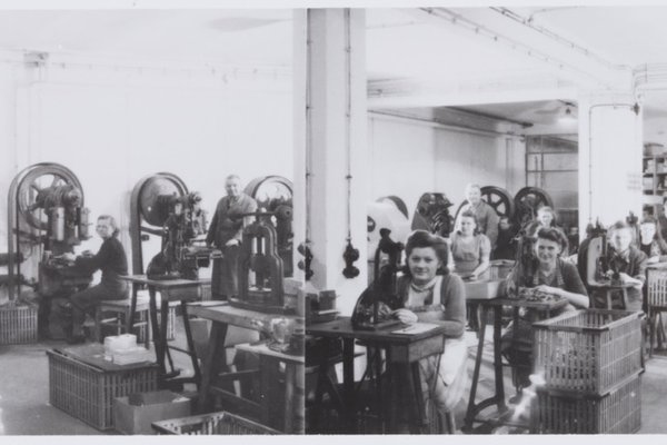 Schwarz-Weiß-Aufnahme einer Werkhalle mit mehreren Beschäftigten an Maschinen und Arbeitsplätzen während der Fertigung, aufgenommen 1938/39.