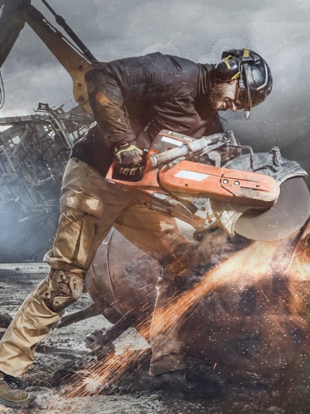 Ein Arbeiter in Schutzausrüstung flext an einem Metallteil