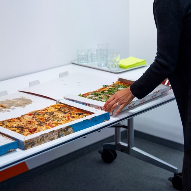 Verschiedene Pizzakartons werden auf einen Tisch gestellt.