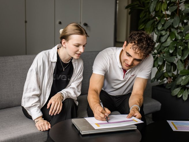 Ein uvex Trainee zeigt einer uvex Werkstudentin etwas auf Papier