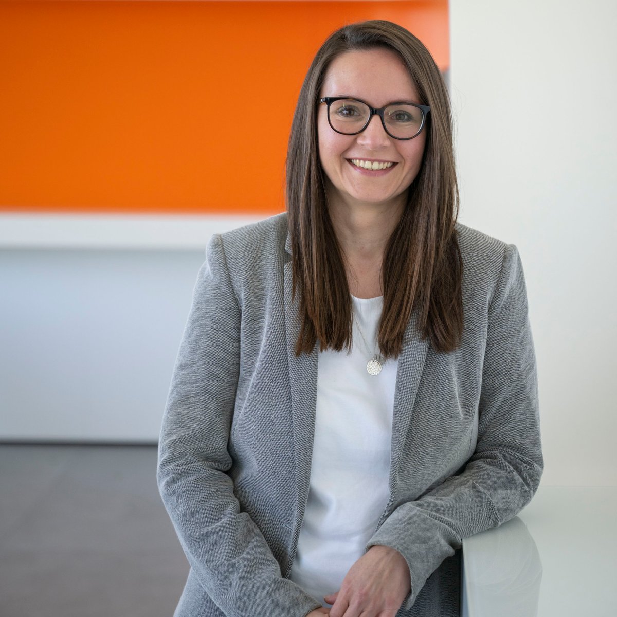 Eine Frau lehnt an einer Wand und lächelt in die Kamera