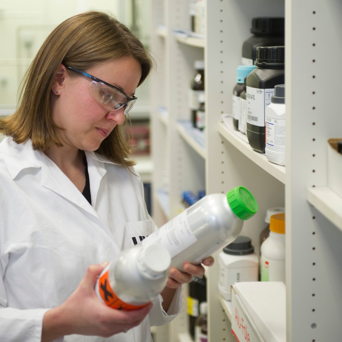 Eine Laborantin betrachtet zwei Flaschen in ihren Händen