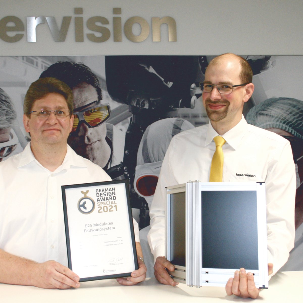 Zwei Personen halten eine Urkunde und einen Bildschirm in den Händen