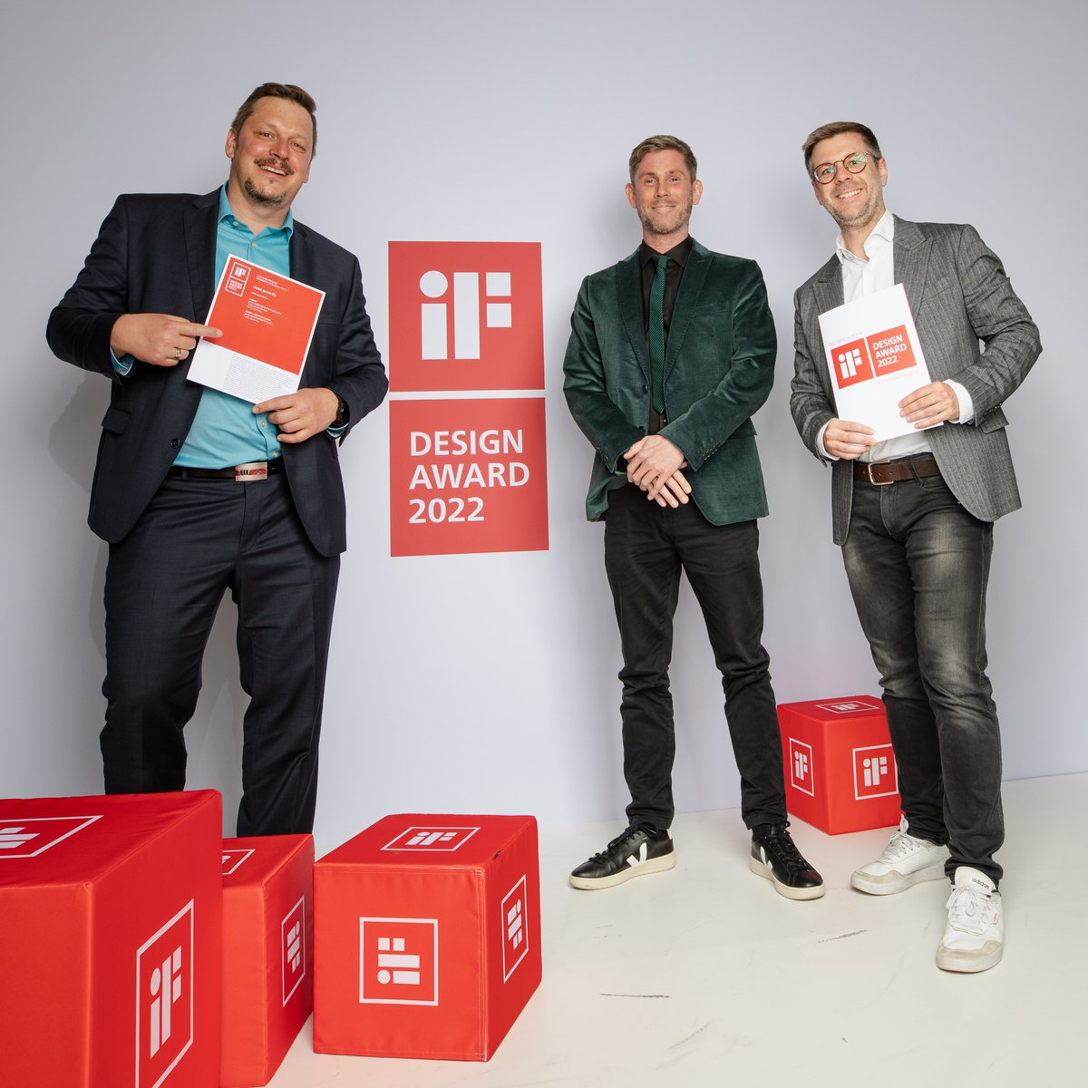 Drei Personen posieren mit einer Urkunde