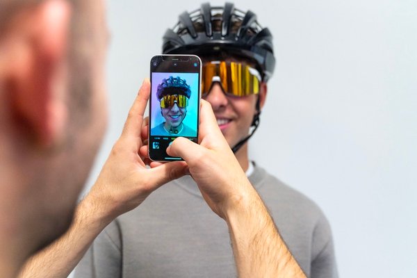 Eine Person macht ein Foto einer anderen Person, die einen uvex Radhelm und Brille trägt