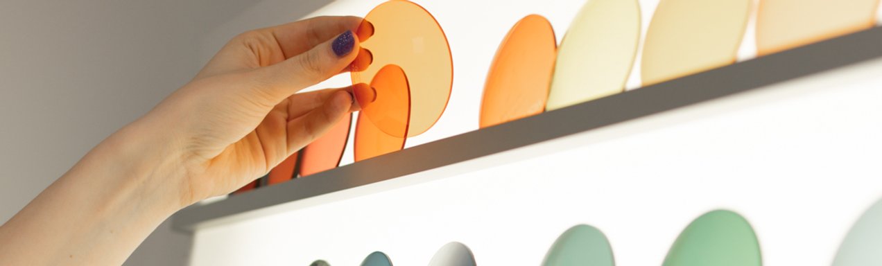 Eine Hand nimmt einen orangenen Glasrohling 